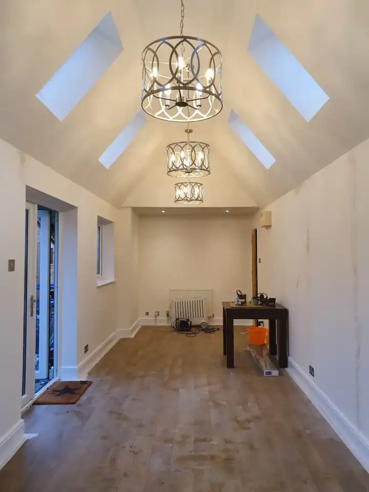 Finished garage conversion looking towards new French doors, with a vaulted ceiling and wood flooring